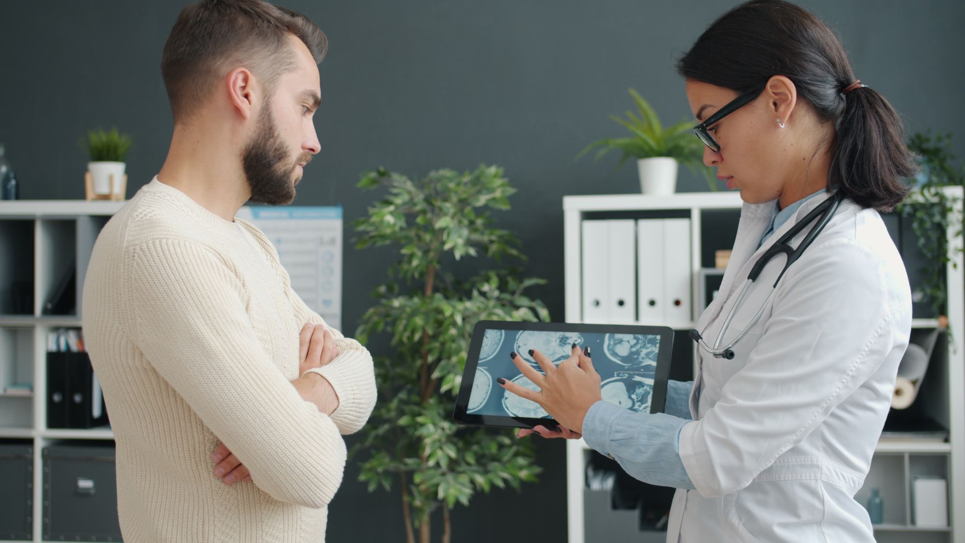 Médico mostrando o resultado de um exame a um paciente em um tablet, no consultório