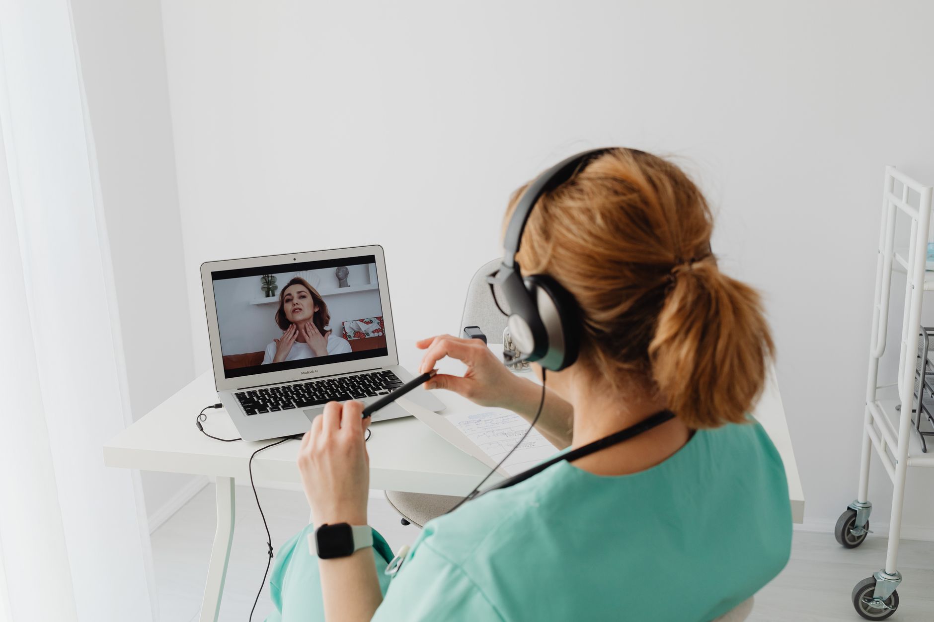 Profissional de saúde conduzindo uma consulta por vídeo em um notebook, no consultório